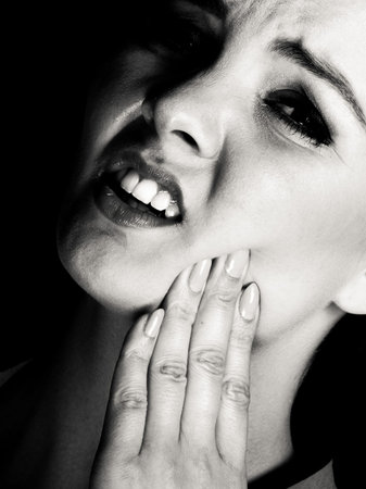 Stress and pain. Face of young painful woman. Female feeling tooth pain ache. Girl touching her mouth teeth by hand.の写真素材