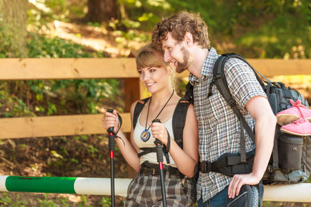 Adventure, tourism, enjoying summer time. Hiking young couple with backpacks tramping on forest road