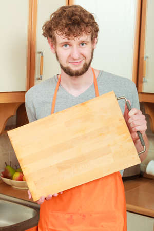 handsome bearded man chef in kitchen interior holds wooden cutting boardの写真素材