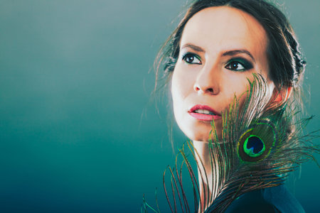 portrait of beautiful woman holding peacock feather