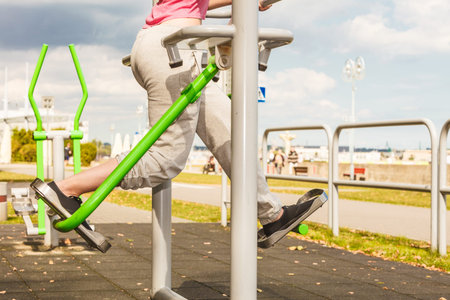 Active woman exercising on elliptical trainer machine.