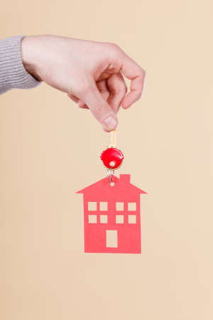 Closeup male hand holding new house key with red home shape.の写真素材