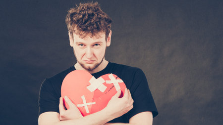 Unhappy sad man guy holding glued on love sign symbol.