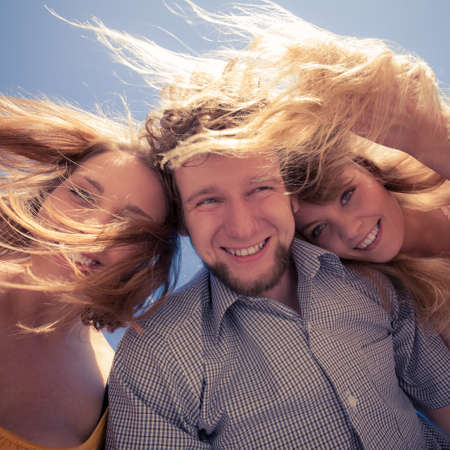Group of friends boy two girls having fun outdoor wind in hair, joy playful moodの写真素材