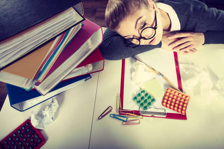 Sick ill young female sleeping at workplace.の写真素材