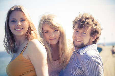 Friendship happiness summer holidays concept. Group of friends boy two girls having fun outdoor enjoying sea breeze sunlight,  joyful mood.の写真素材