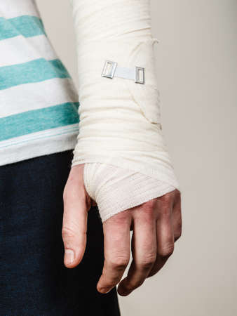Fractures and dislocations concept. Part body male with hand in bandage. Helpful medication for painful palm arm of young man.の写真素材