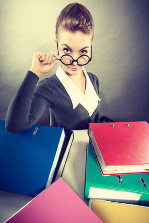 Lovely woman surrounded of piles of colorful binders.の写真素材