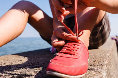 Young girl tying shoelace.の写真素材