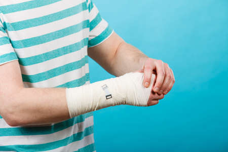 Young man holds bandaged hand.の写真素材