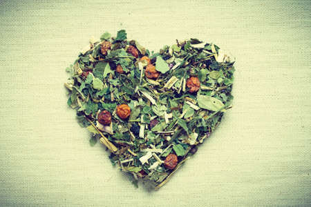 Dried herb leaves heart shaped on burlap jute surface.の写真素材