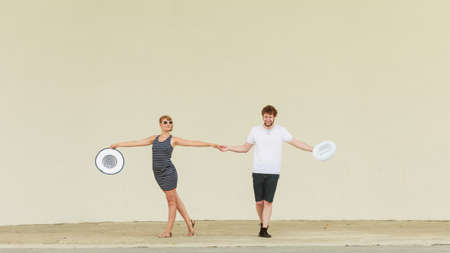 Fashion couple posing outdoor on stage. Woman in striped dress and hat and man in white shirt.の写真素材