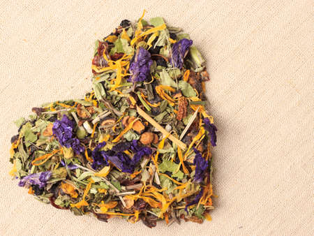 Dried herb leaves heart shaped on burlap surface.の写真素材