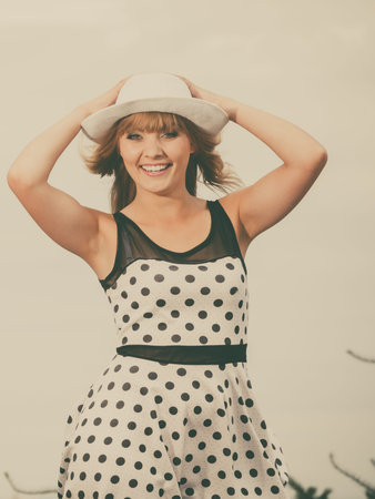 young beautiful caucasian woman retro styling wearing polka dot dress hat outdoorの写真素材
