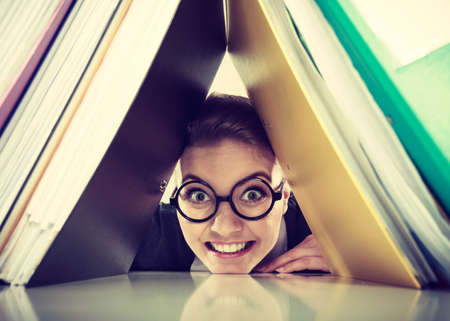 Happiness and satisfaction from working. Young positive happy blonde accountant at work. Crazy lovely woman surrounded of piles of colorful binders.の写真素材