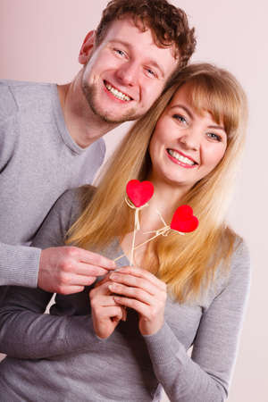 Happiness in love. Lovely charming couple smiling. Happy joyful woman and man holding little hearts on sticks. Two people with sign symbol of good relationship feelings.の写真素材