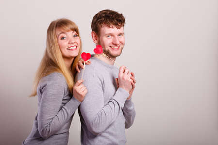 Happiness in love. Lovely charming couple smiling. Happy joyful woman and man holding little hearts on sticks. Two people with sign symbol of good relationship feelings.の写真素材