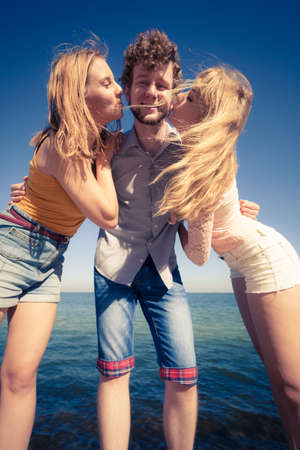 Friendship happiness love concept. Group of friends boy two girls having fun outdoor, women kissing man wide angle viewの写真素材