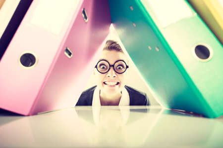 Happiness and satisfaction from working. Young positive happy blonde accountant at work. Crazy lovely woman surrounded of piles of colorful binders.の写真素材