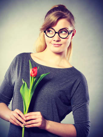 Dreams and hope concept. Young blonde smiling woman dreaming about something positive. Girl with tulip dream of future celebration.の写真素材