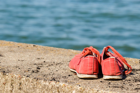 Travel footwear hiking leisure holidays symbol. Pair of shoes at seafront. Two boots on wall.