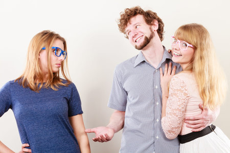 Jealousy and betrayal concept. Abandoned jelous girl watching on happy hugging couple. Triangle relationship.の写真素材