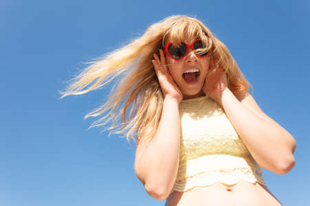 Summer, happiness and lifestyle concept. Lovely blonde girl in sunglasses relaxing outdoor against blue sky, wide angle unusual viewの写真素材