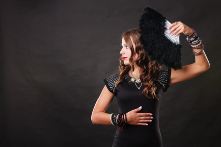 Portrait of beautiful brunette woman with black feather fan in hand