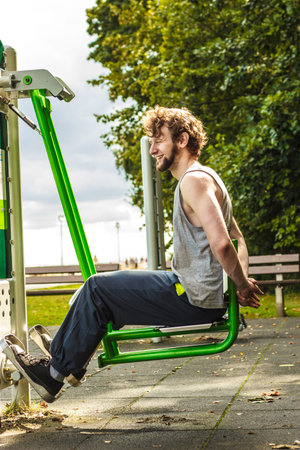 Active young man exercising on leg press machine. Muscular strong guy in training suit working out...