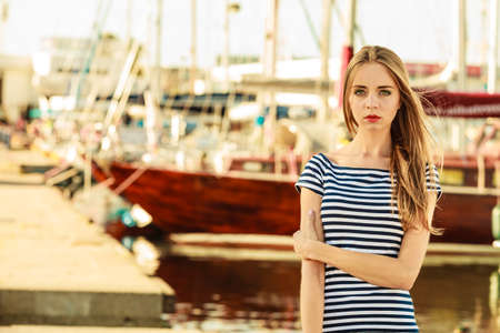 Travel tourism and people concept. Fashion blonde girl in marina against yachts in portの写真素材