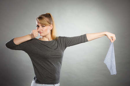 Household duties concept. Young disgust girl holding cleaning cloth rag doing domestic chores. Unhappy housewife.の写真素材