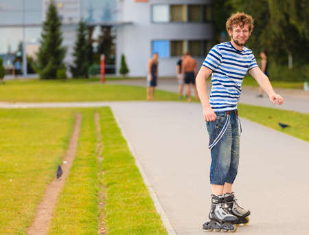 Holidays, active lifestyle freedom concept. Young fit man on roller skates riding outdoors on street, guy rollerblading on sunny dayの写真素材