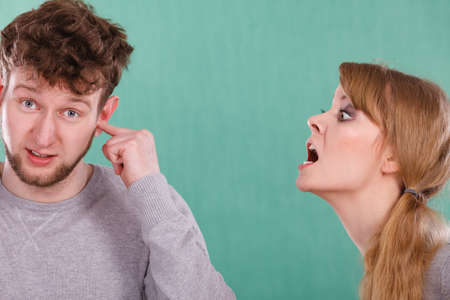 Violence against man. Aggressive woman yelling shouting on scared afraid man. Negative relations in partnership. Expressive young lady screaming.の写真素材