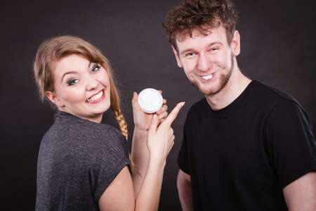 Beauty cream health concept. Young couple and skin care. Girl puts cream on man face.の写真素材