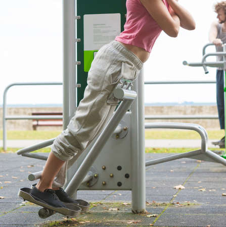 Active woman exercising on backtrainer. Sporty fit girl in training suit working out at outdoor gym. Sport fitness and healthy lifestyle concept.の写真素材
