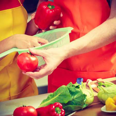 Healthy eating, vegetarian food, cooking, dieting and people concept Happy young couple woman and man having fun in kitchen at home preparing fresh vegetables saladの写真素材