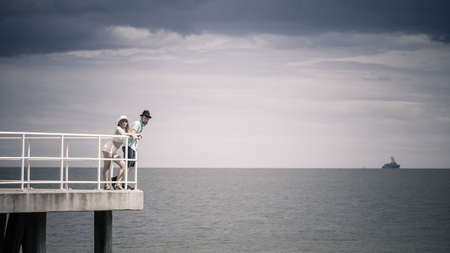 Summer vacation. Loving hipster couple woman and man spending leisure time together walking on sea pierの写真素材