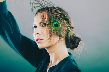 portrait of beautiful woman holding peacock feather