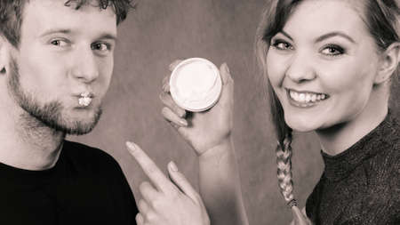Beauty cream health concept. Young couple and skin care. Girl puts cream on man face.の写真素材