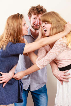 Aggressive mad women fighting over man. Jealous girls wooing guy. Violence.の写真素材
