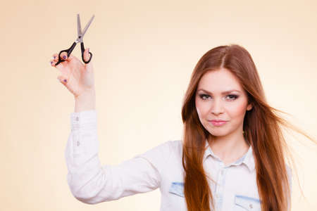 Beauty danger haircut coiffure care concept. Smiling lady showing tools. Young cheerful irresponsible hairdresser waving around razor sharp scissors, holding special chunking texturizing shearsの写真素材
