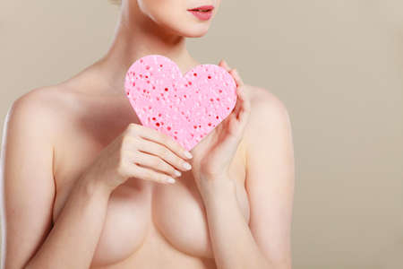 Skincare hygiene medicine and body treatment. Sensual naked woman with beautiful figure perfect skin holding pink heart shaped sponge in hands.の写真素材