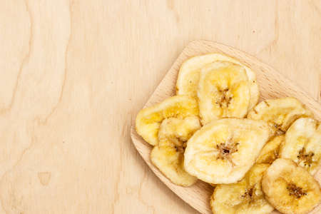 Heap of banana chips, dehydrated slices on wooden spoonの写真素材