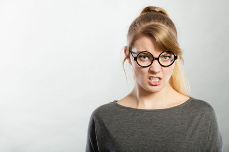 Anger and rage concept. Young expressive woman show her bad face. Angry nervous annoyed girl...
