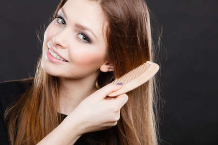 Preparation to evening party. Gorgeous attractive woman combing her long straight smoothy healthy hair before go out. Party and celebration concept.の写真素材