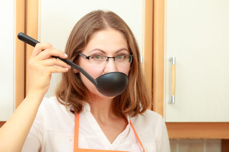 Housewife tasting soup meal dinner. Middle aged woman holding spoon ladle. Housekeeper preparing...