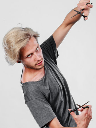 Haircut coiffure haircare concept. Passionate male hairdresser holding scissors showing work tools...