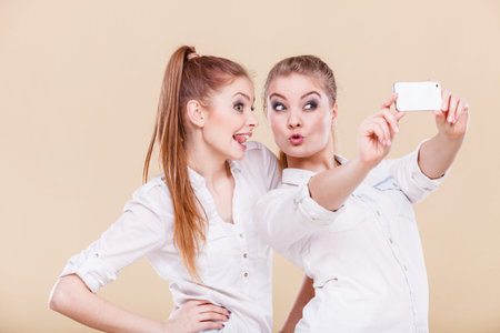 Fun bonding selfie concept. Sisters or best friends, two student blonde girls taking self photo with...