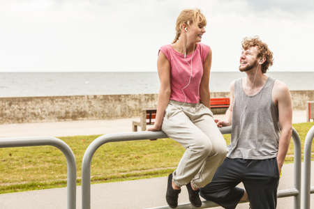 Woman and man with earphones listening to music outdoor taking break from fitness exercise.の写真素材