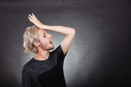 Young man confused thinking seeks a solution. Decision making process, creativity concept, studio shot on dark.の写真素材